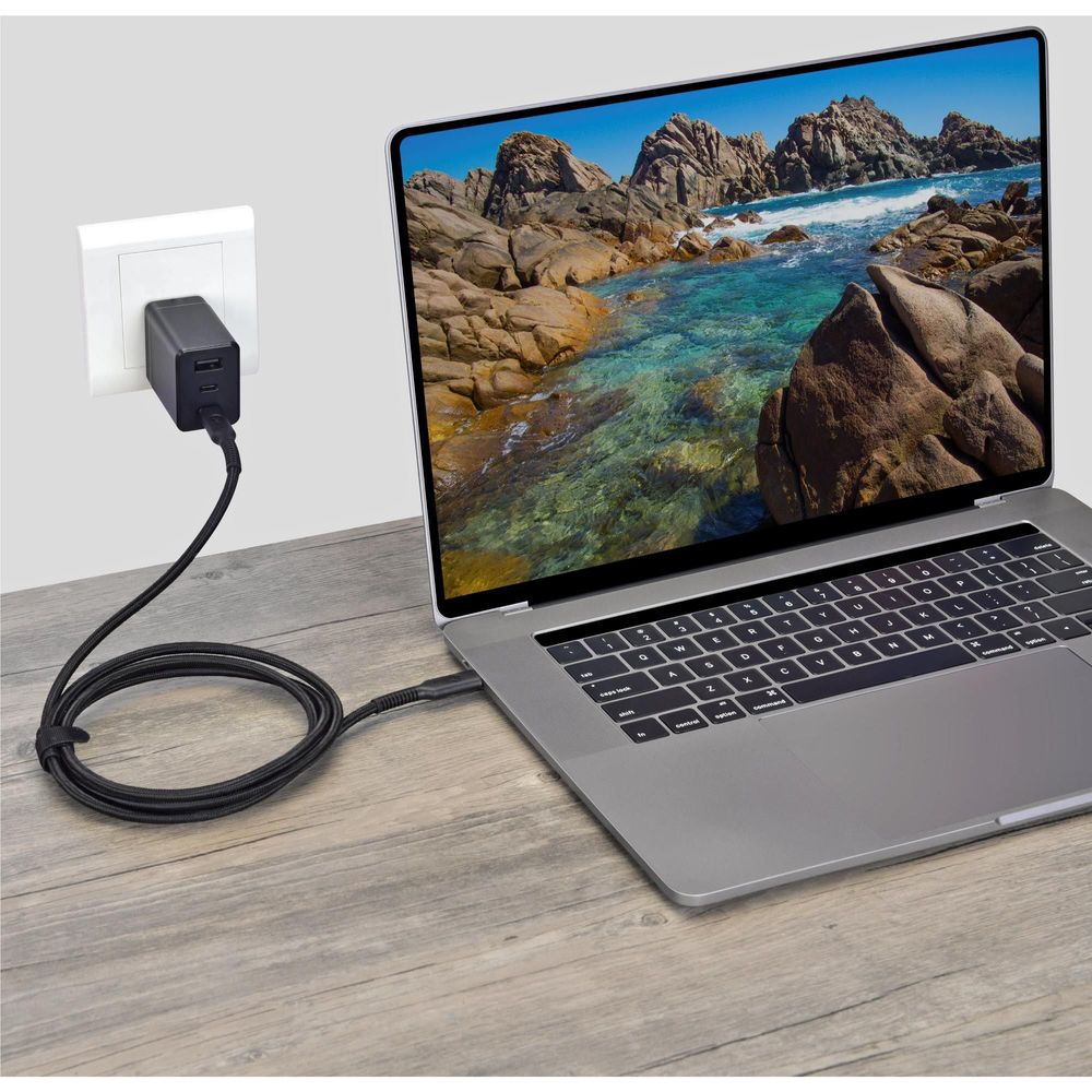 USB-C cable plugged into wall adapter and laptop on a desk