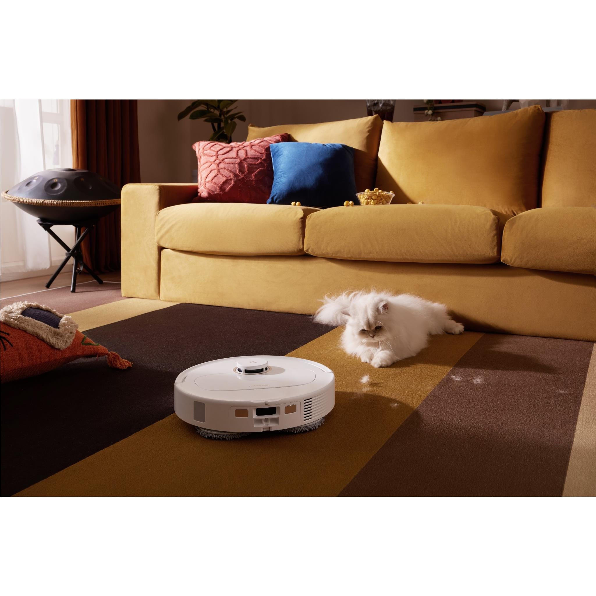 White robot vacuum and mop moving across living room floor near a pet.
