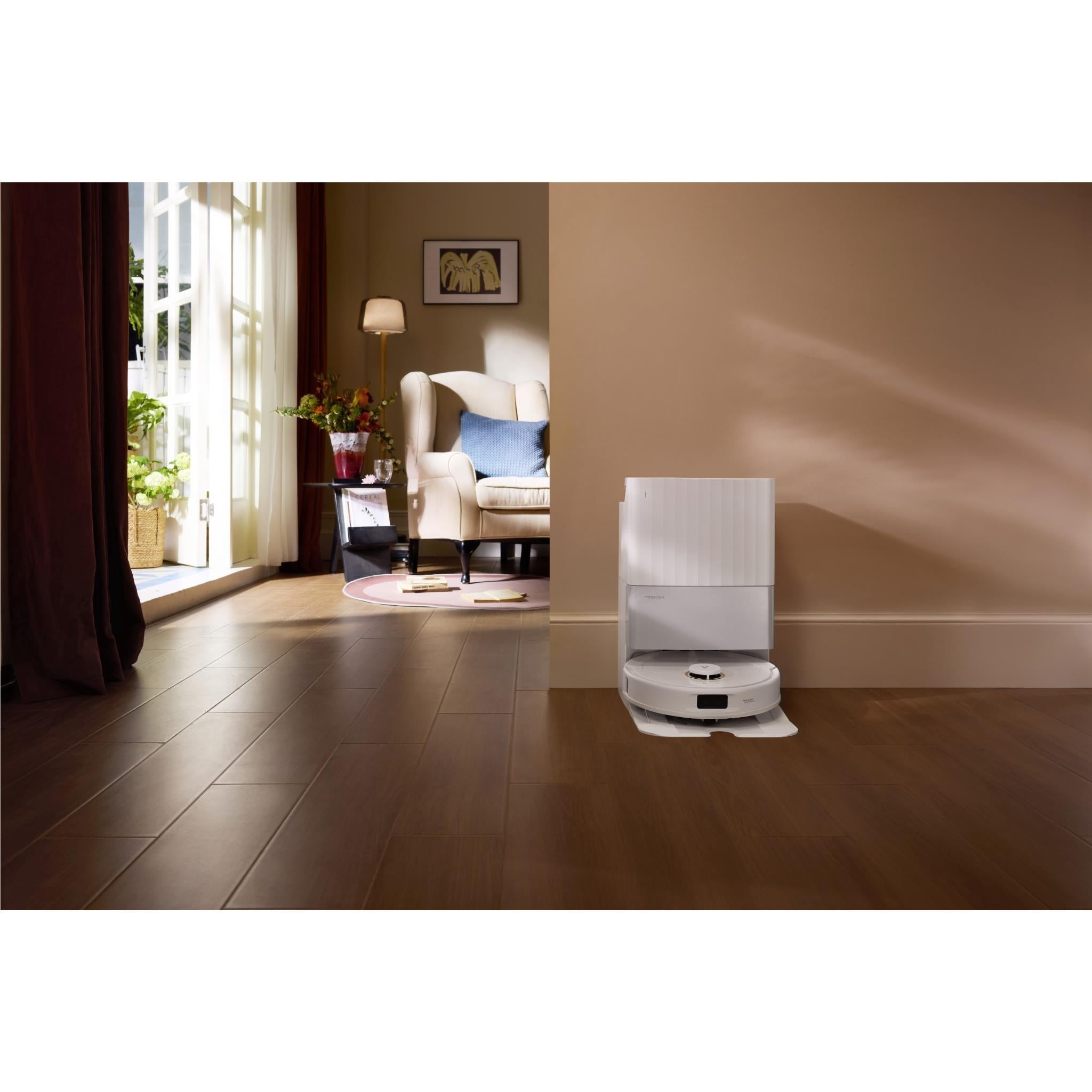 White robot vacuum and mop docked near a wall in a room.