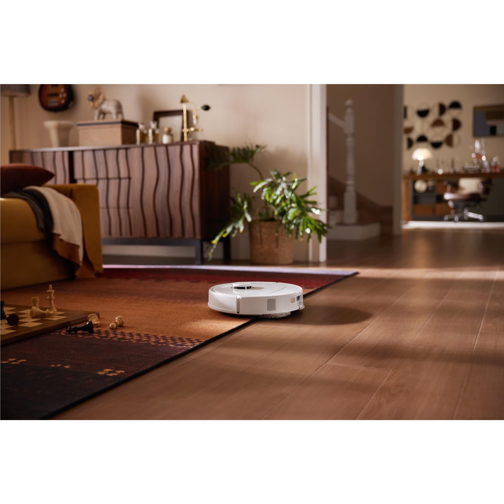 White robot vacuum and mop cleaning on hardwood floor near a rug.