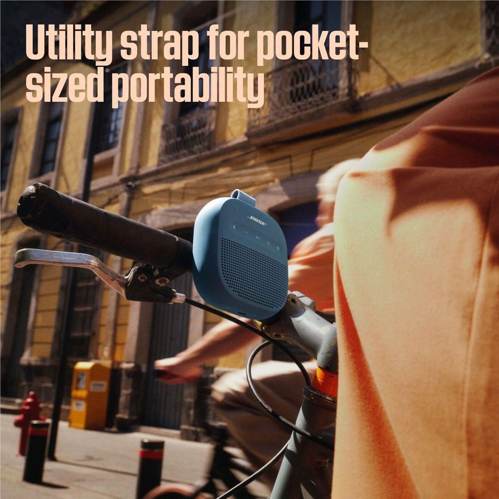 Blue Bose SoundLink Micro portable speaker on bike handlebar with strap