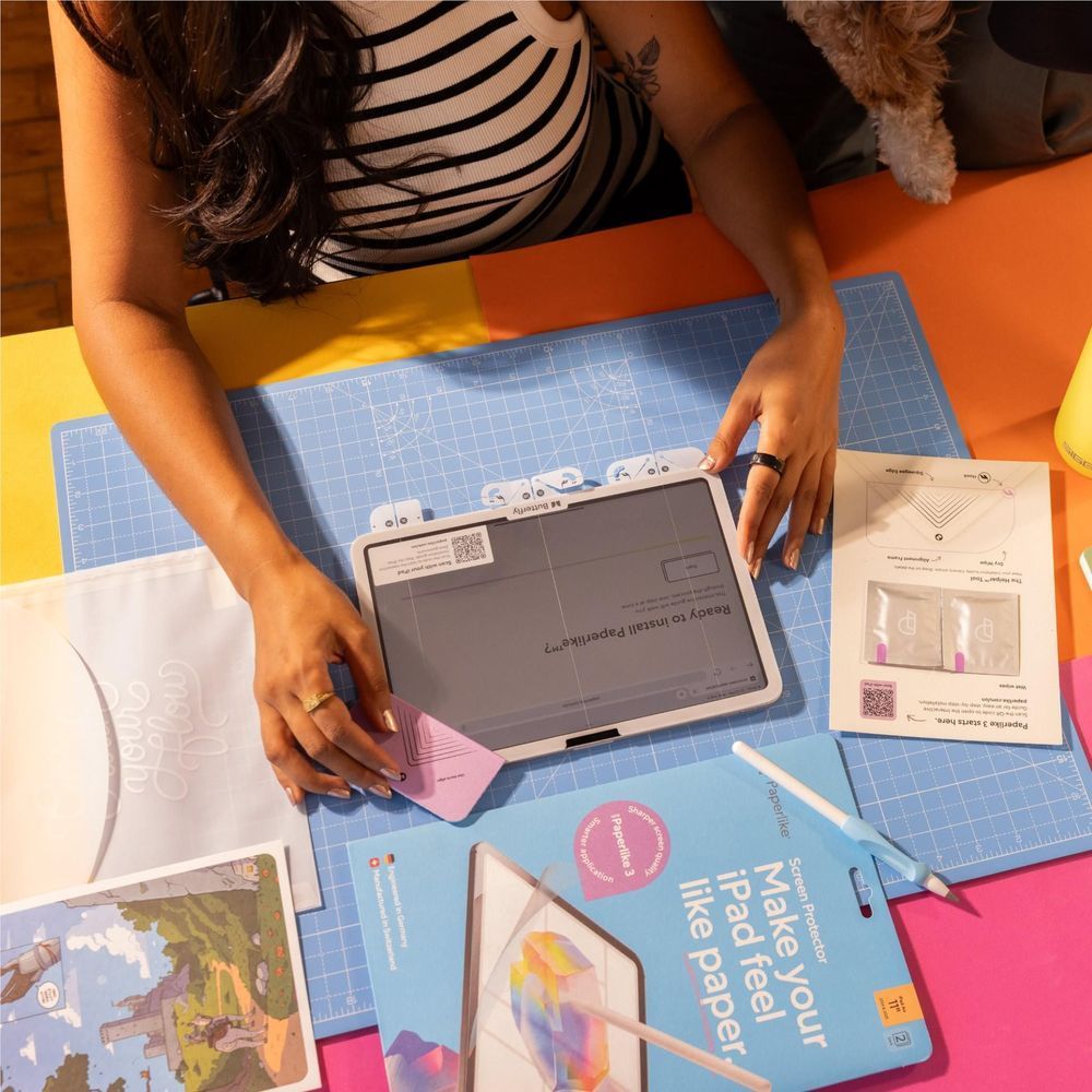 Screen protector installation on an iPad with tools and protective sheets nearby