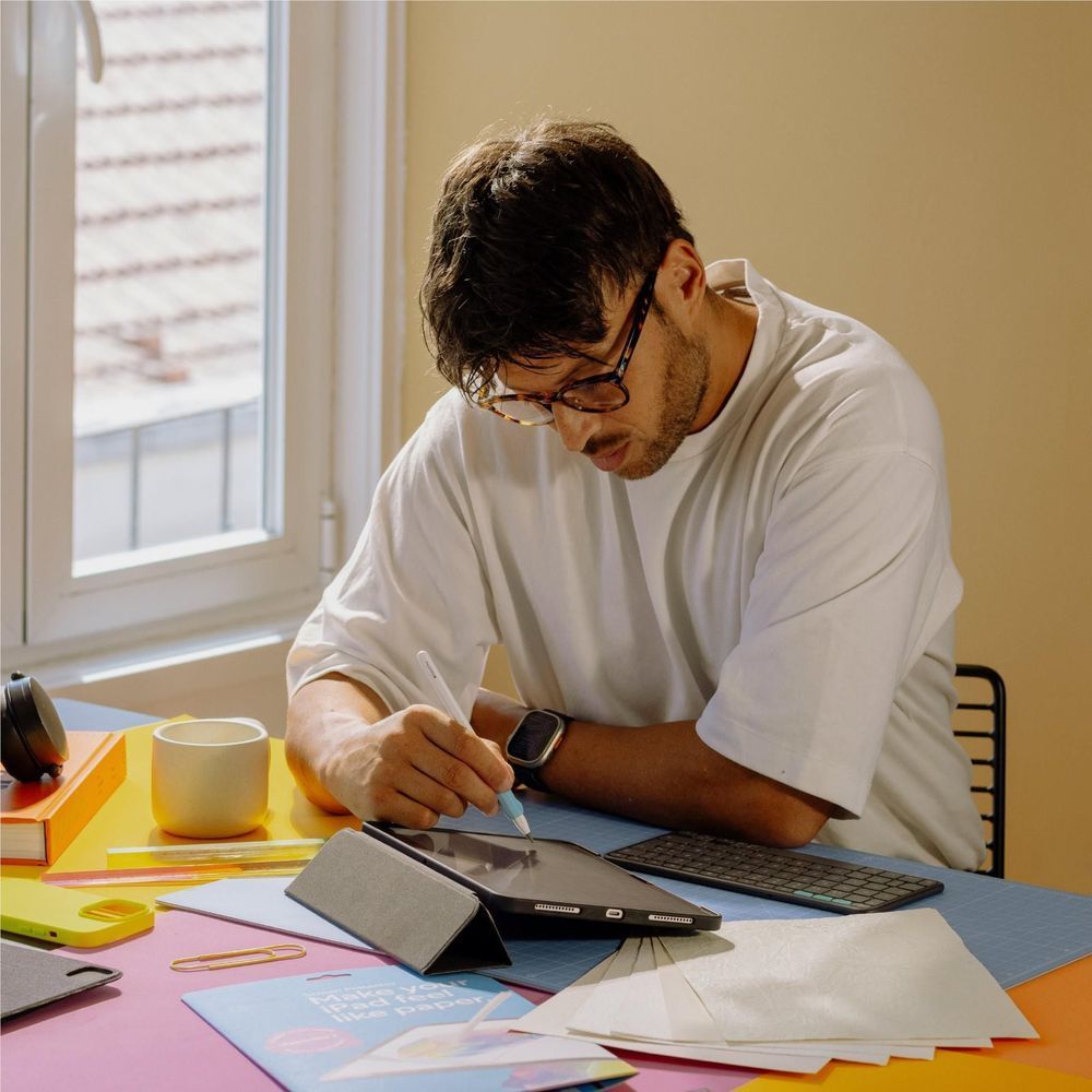 iPad Pro on desk with a screen protector being applied by hand