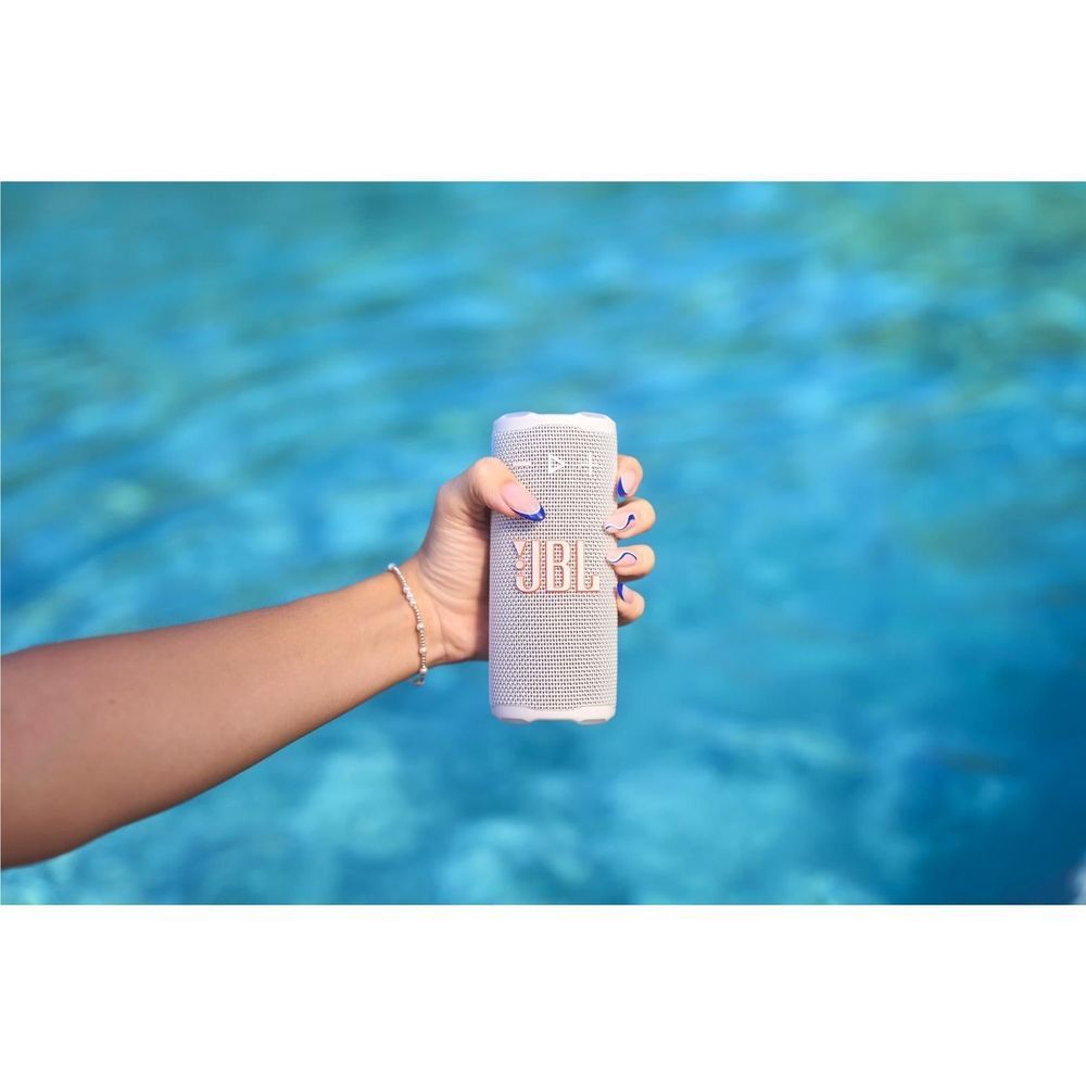 White JBL portable speaker held in a hand, textured mesh body visible