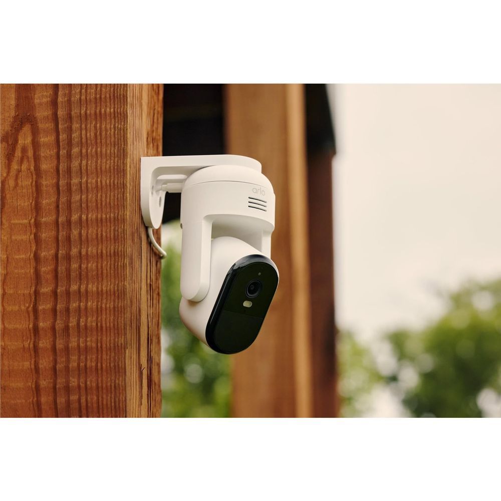 White plug-in security camera mounted to a wooden wall with dark lens cover