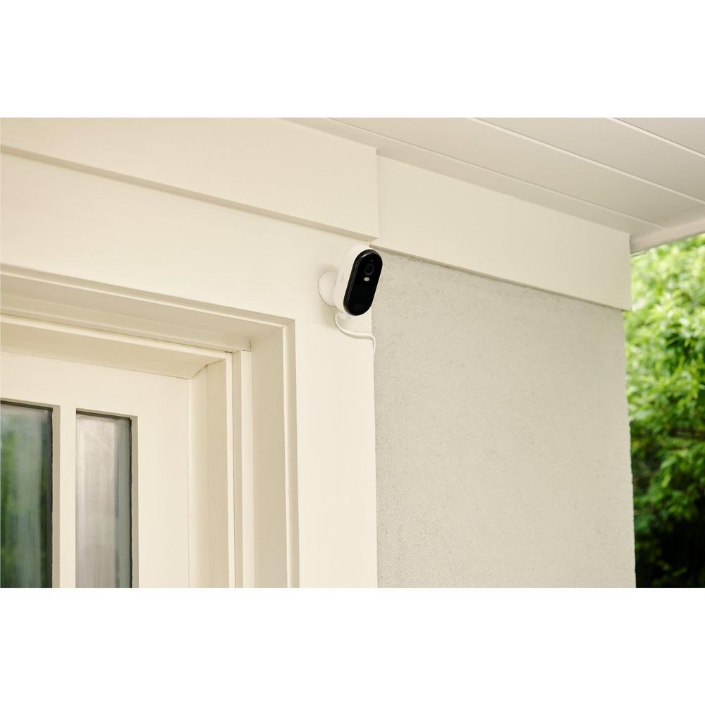 Outdoor security camera mounted under eave on a light exterior wall