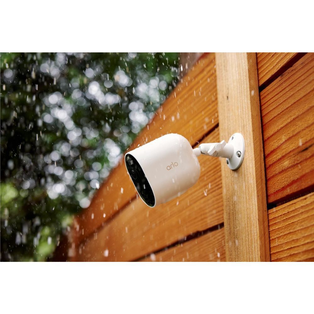 White outdoor security camera mounted on wood siding, lens facing outward
