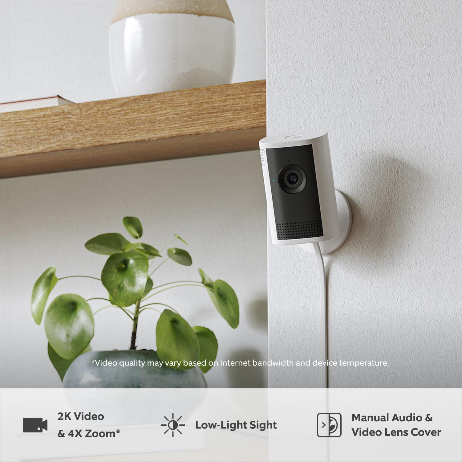White indoor security camera mounted on wall with black lens window and grille