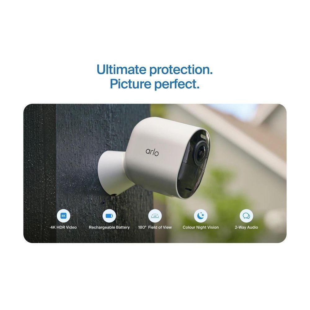 Outdoor security camera in white housing with lens and side mount on dark wall