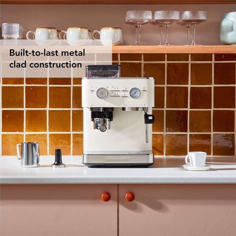 Porcelain espresso machine with grinder on counter, with metal milk pitcher and cups