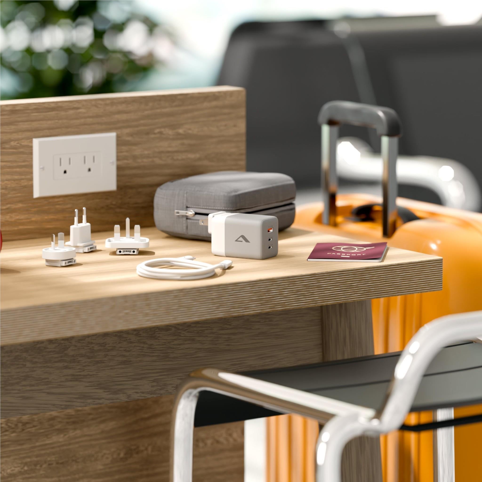 Compact travel charger with fabric case, plug adapters, and USB cables on desk