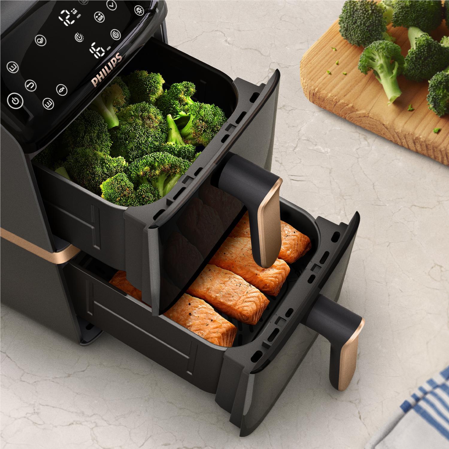 Dual-basket air fryer with broccoli and salmon in separate open baskets, black body.