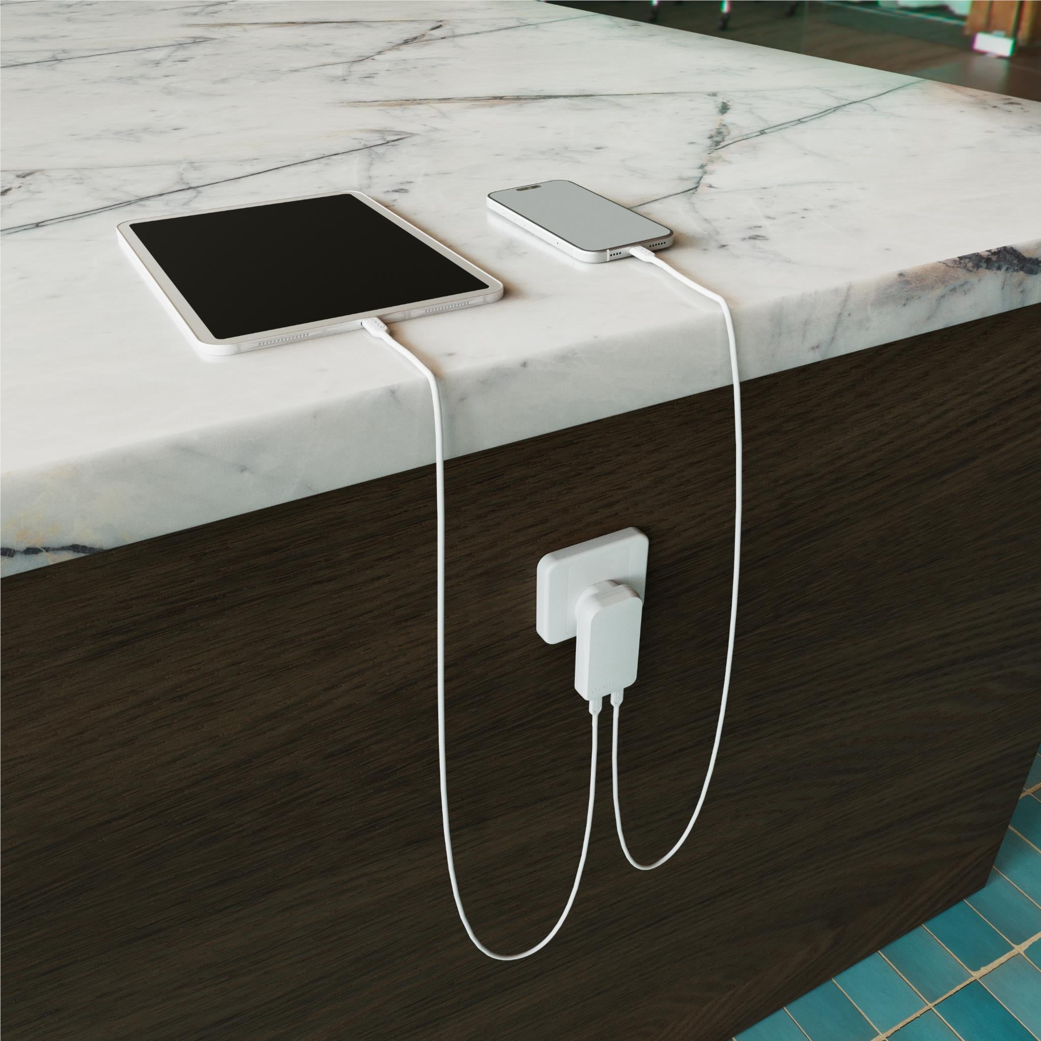 White wall charger connected to devices on desk with charging cables
