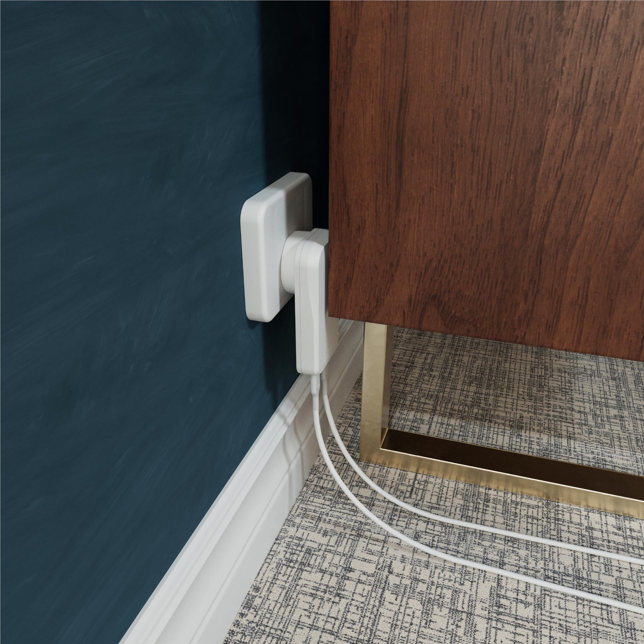 White wall charger plugged into outlet near baseboard with charging cables