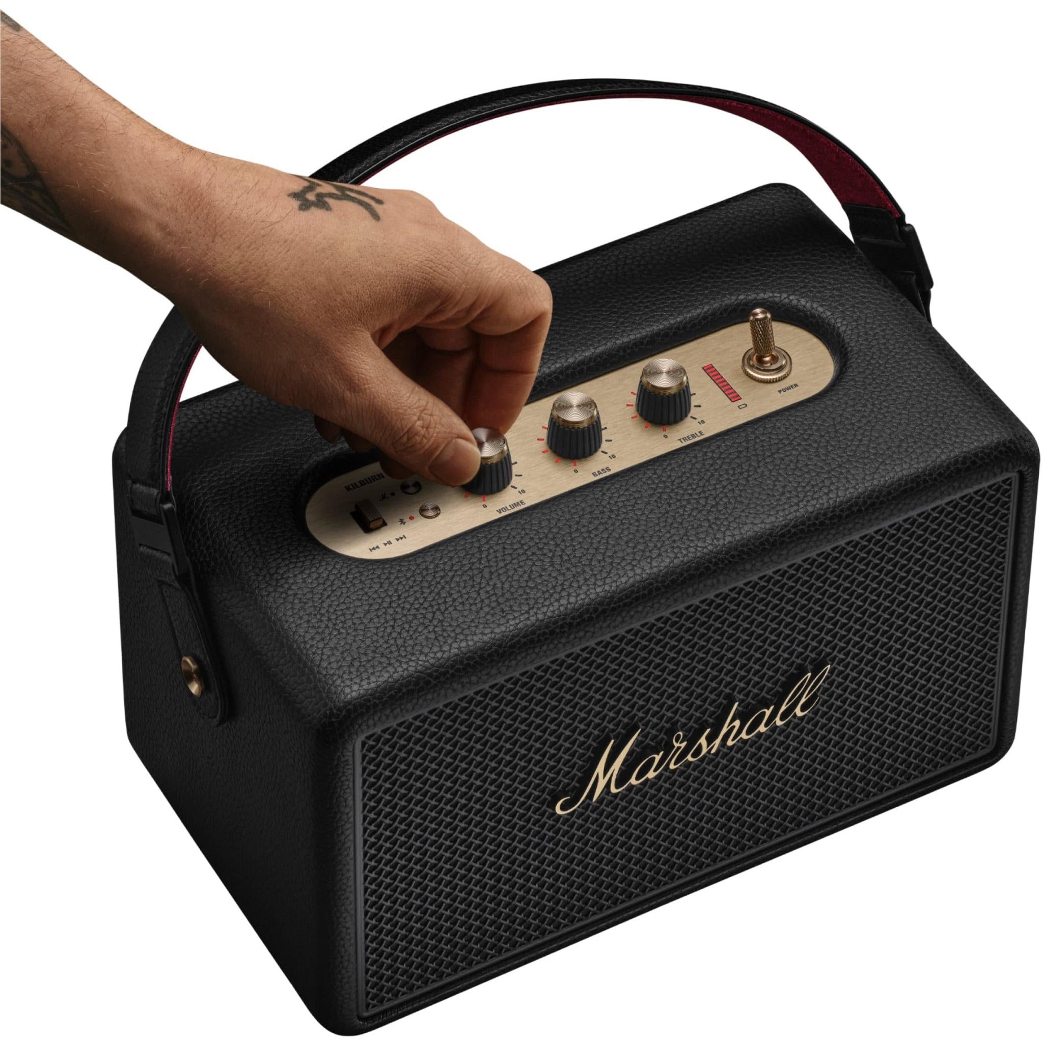 Black Marshall portable speaker with brass control panel, held by hand