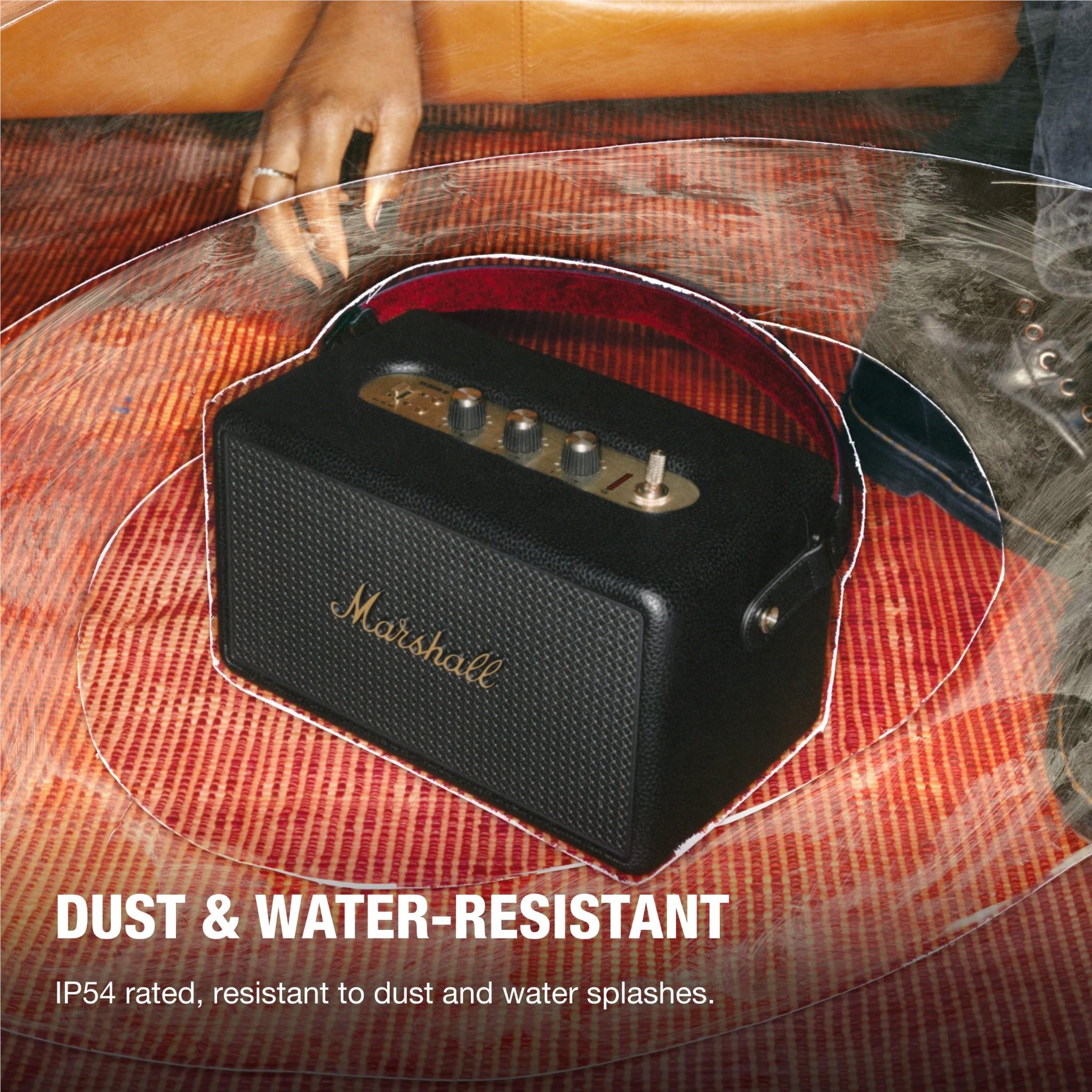Black Marshall portable Bluetooth speaker with brass controls on patterned rug