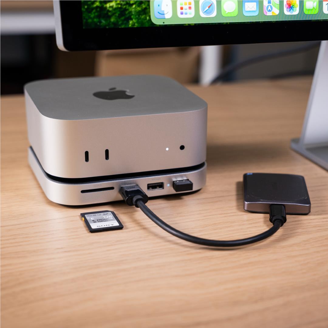 Silver Mac mini stand hub on desk with cable and exposed SSD module