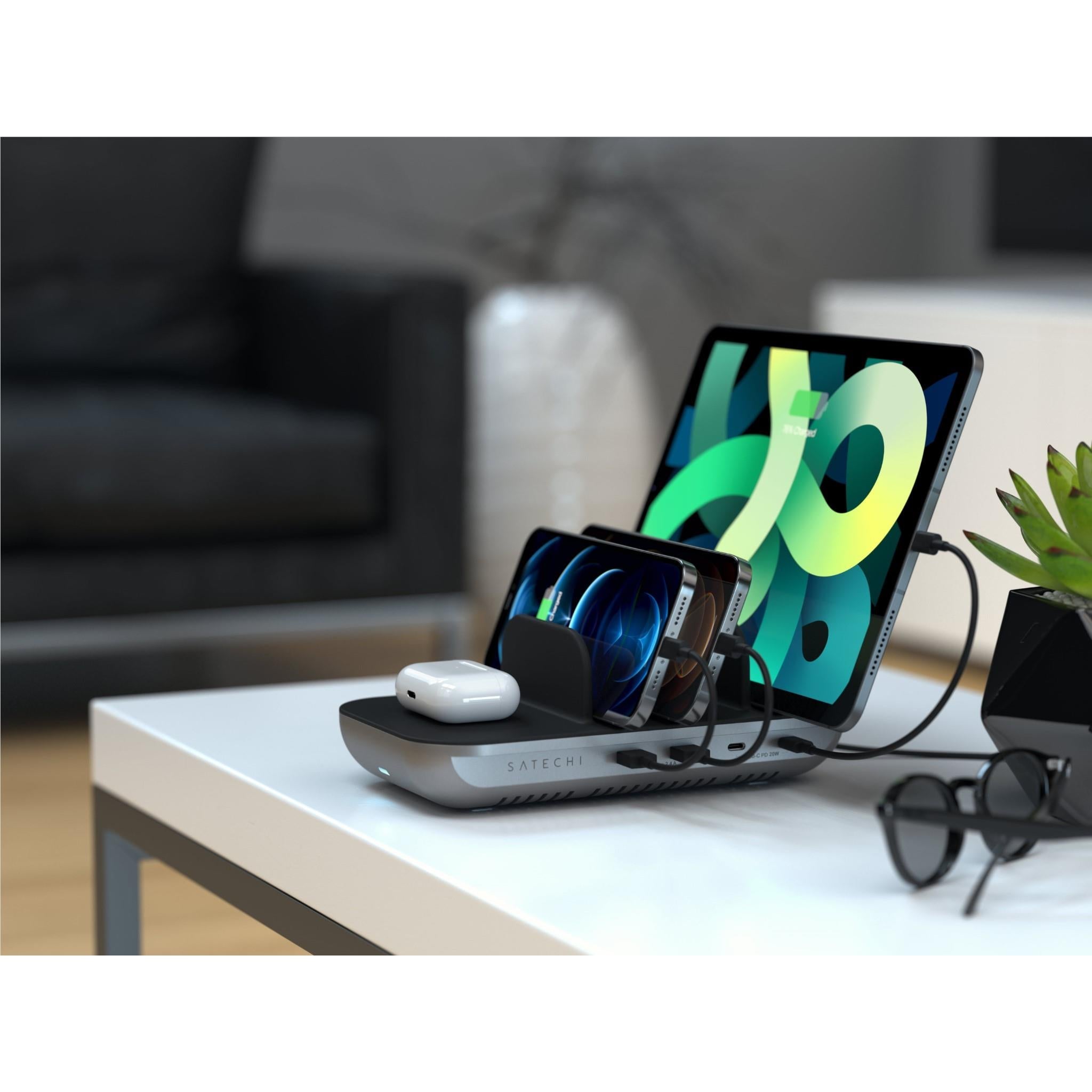 Black 5-port charging station on desk with wireless pad charging a phone