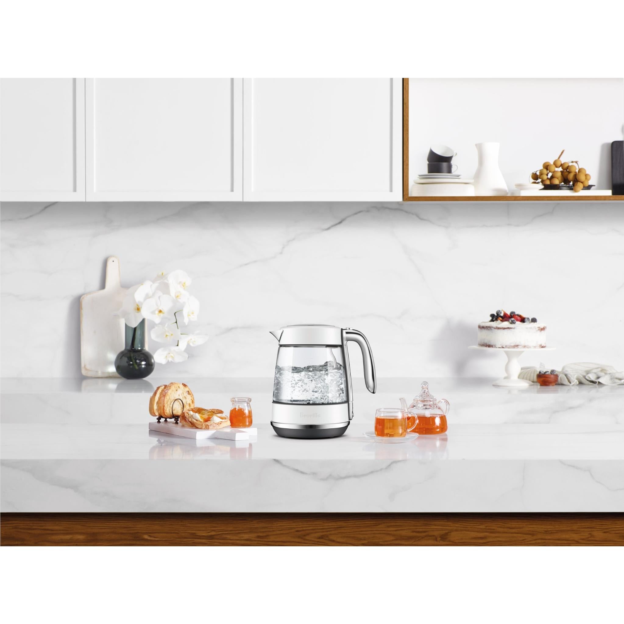 Stainless glass jug electric kettle on countertop with cups and tea nearby