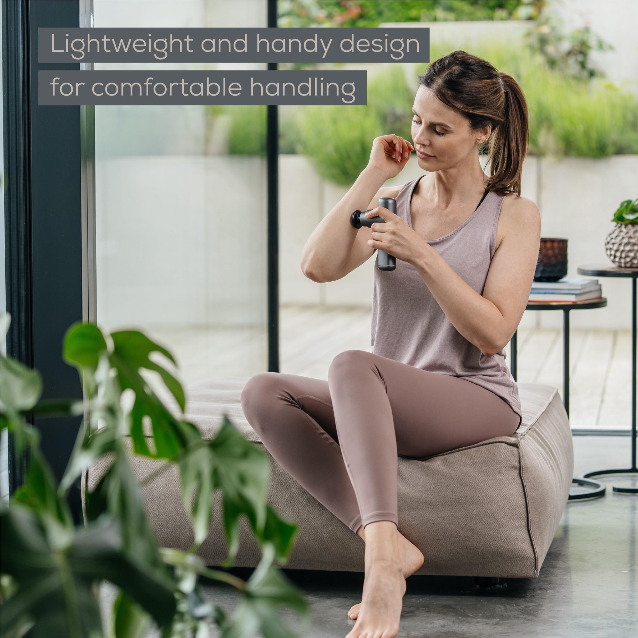 Grey portable massage gun held in hand for comfortable use