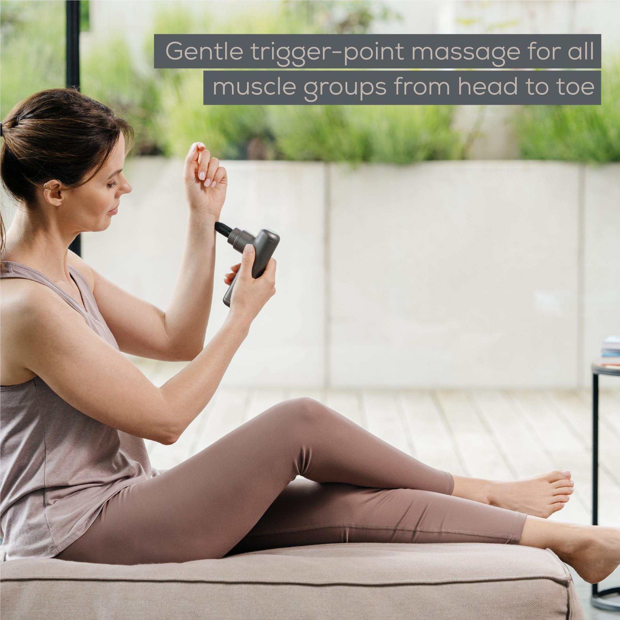 Grey massage gun held against upper arm area with a small head