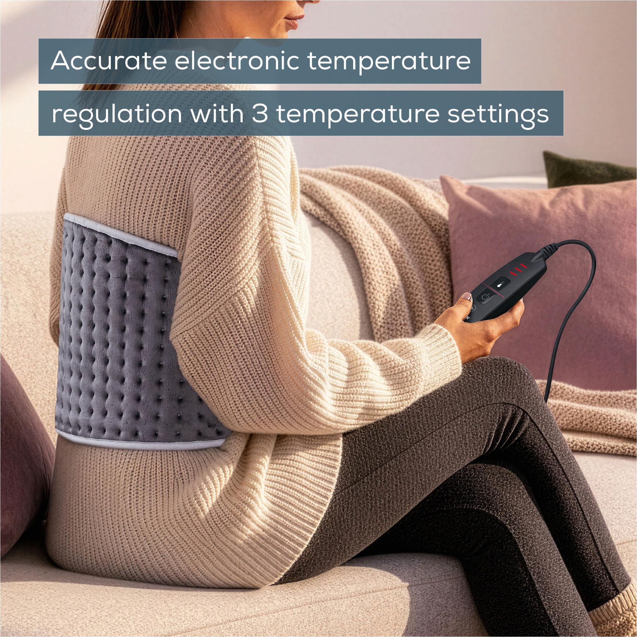 Grey fleece heat pad wrapped on back with controller held in hand