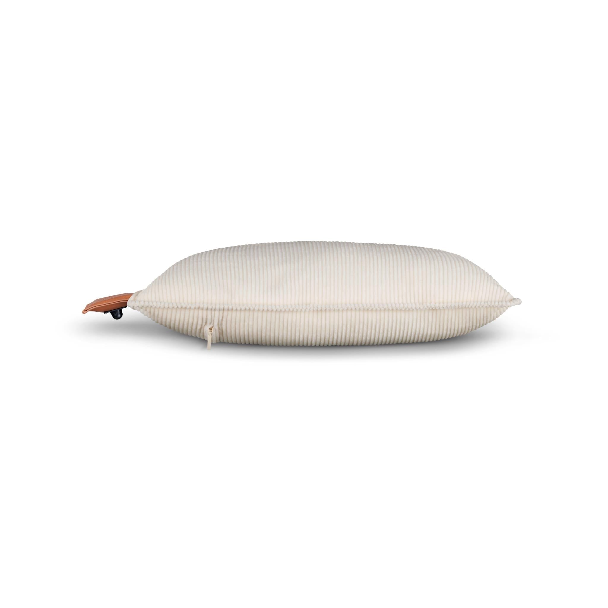 Cordless heated cushion in light cream with ribbed cover and brown leather control tag.