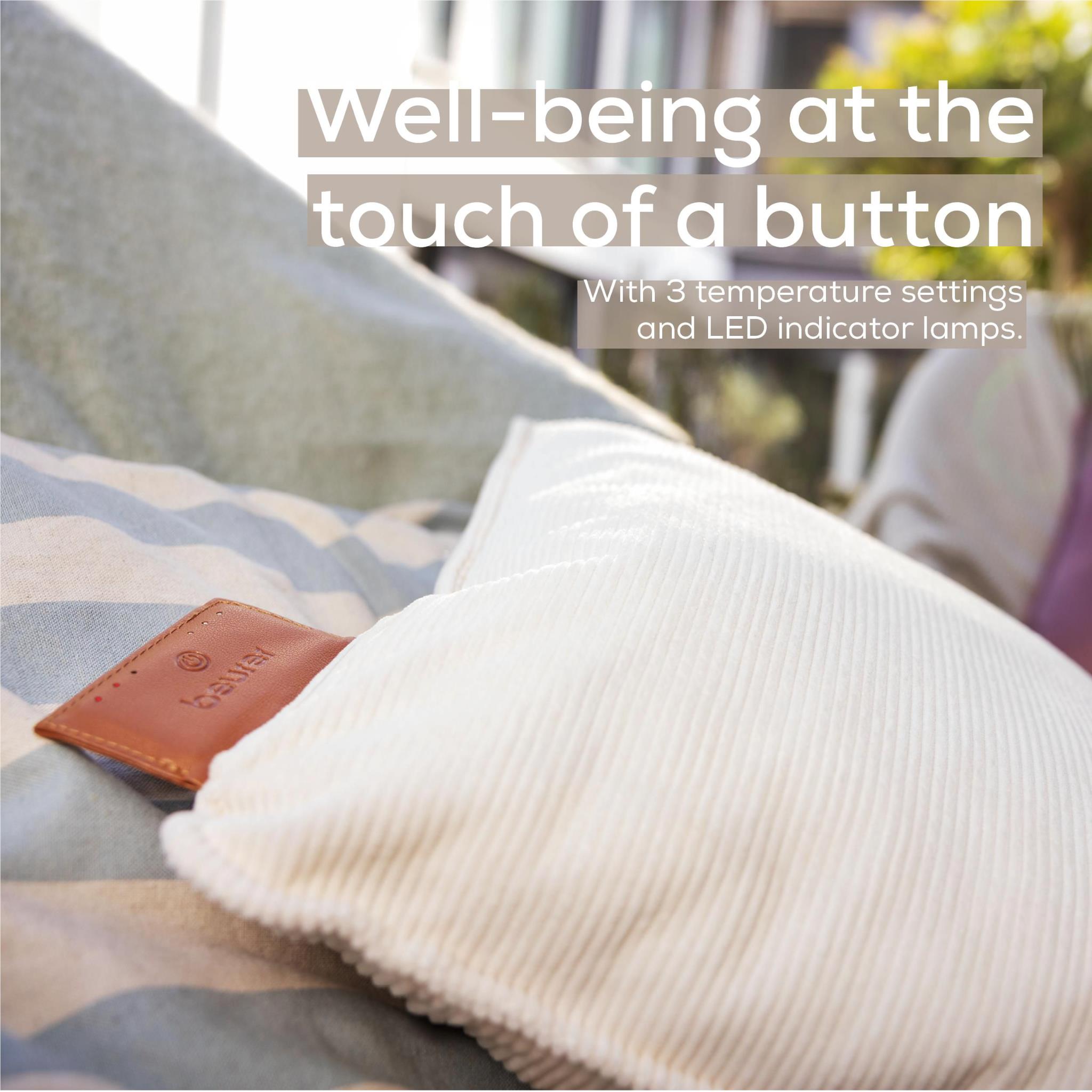 Light cream heated cushion on a sofa with brown leather control patch visible.