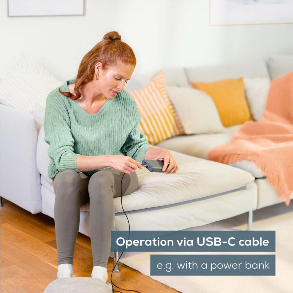 Grey heated foot massager cushion with USB-C cable used on seated legs