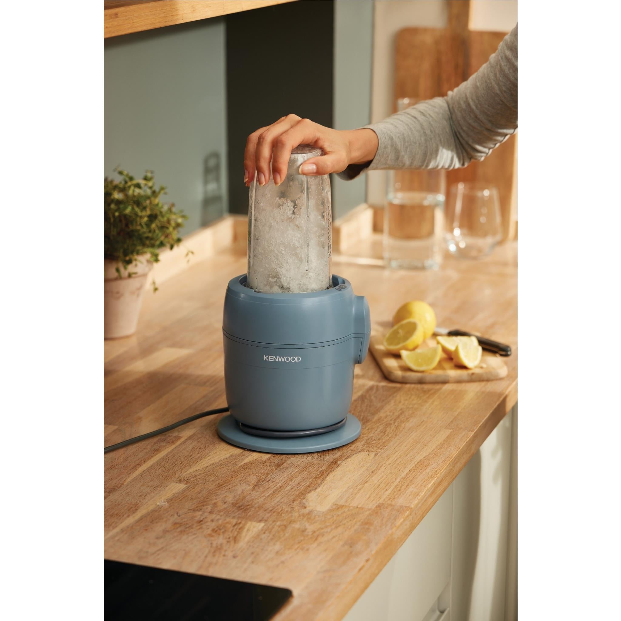 Storm Blue food processor on countertop with clear jug and hand adding ingredients