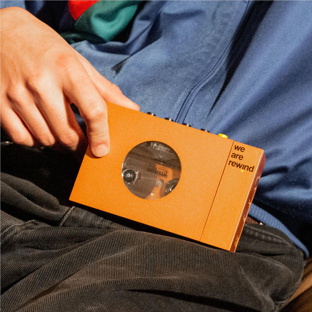 Orange cassette tape player held in hands with round tape window