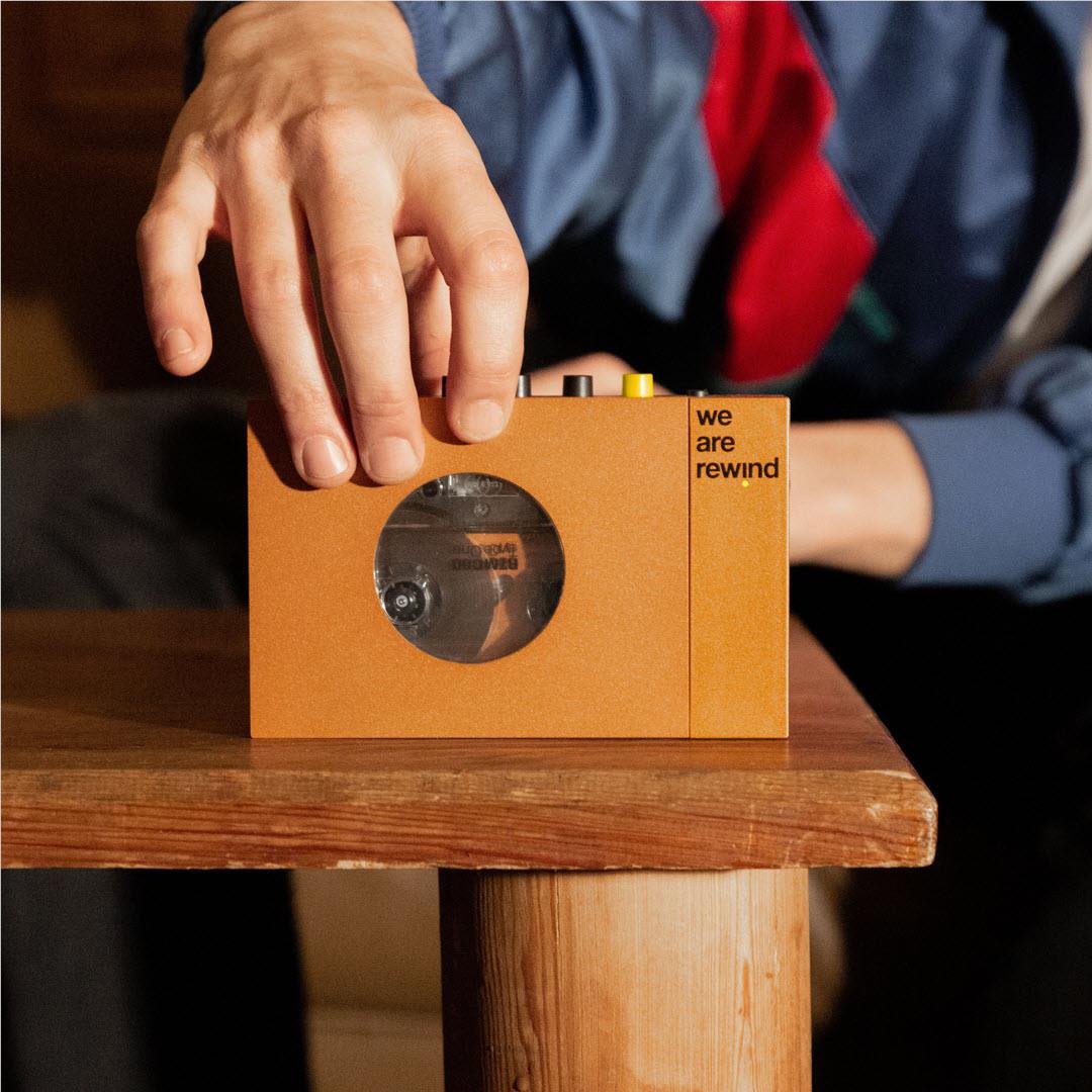 Orange cassette tape player on wooden surface with top control buttons