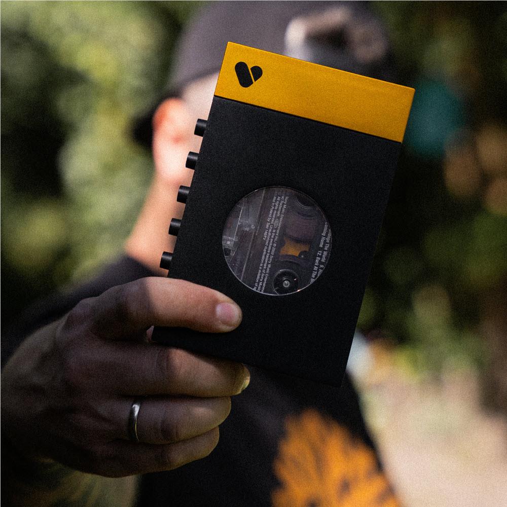 Bluetooth cassette player in hand, black front with circular window and yellow top