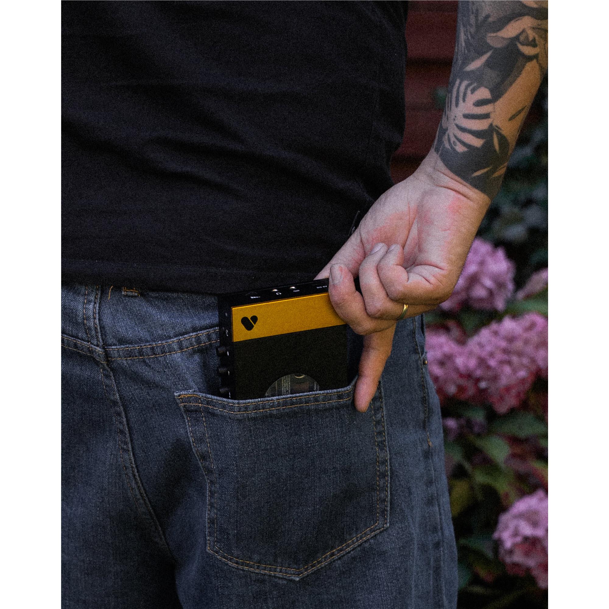 Bluetooth cassette player clipped in pocket, yellow label on black case