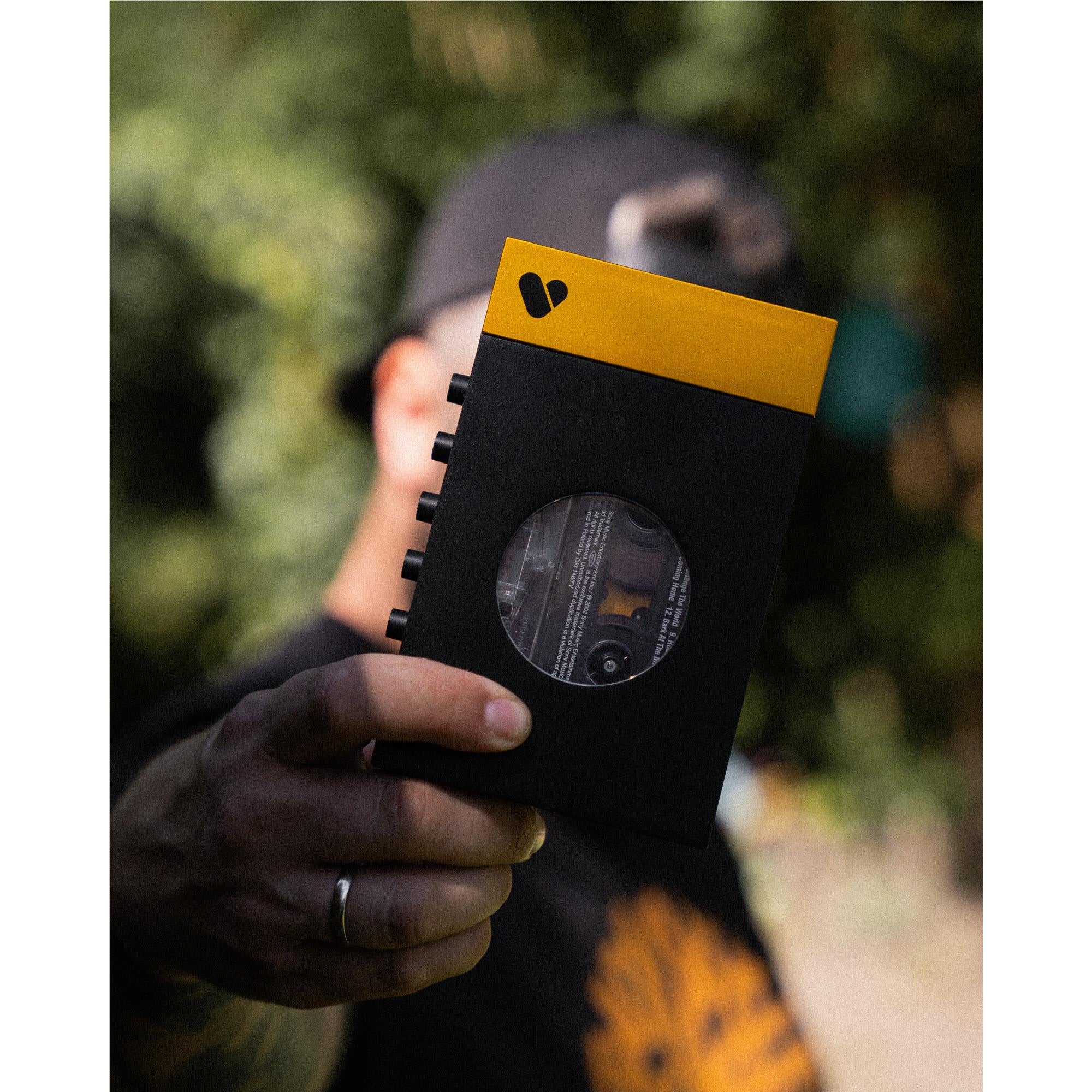 Bluetooth cassette player in hand, front circular window with yellow accent