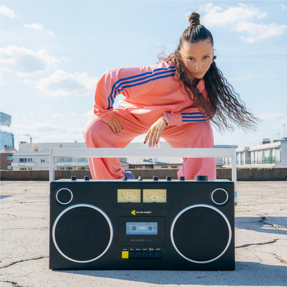 Black cassette boombox on rooftop with twin speakers and cassette display panel