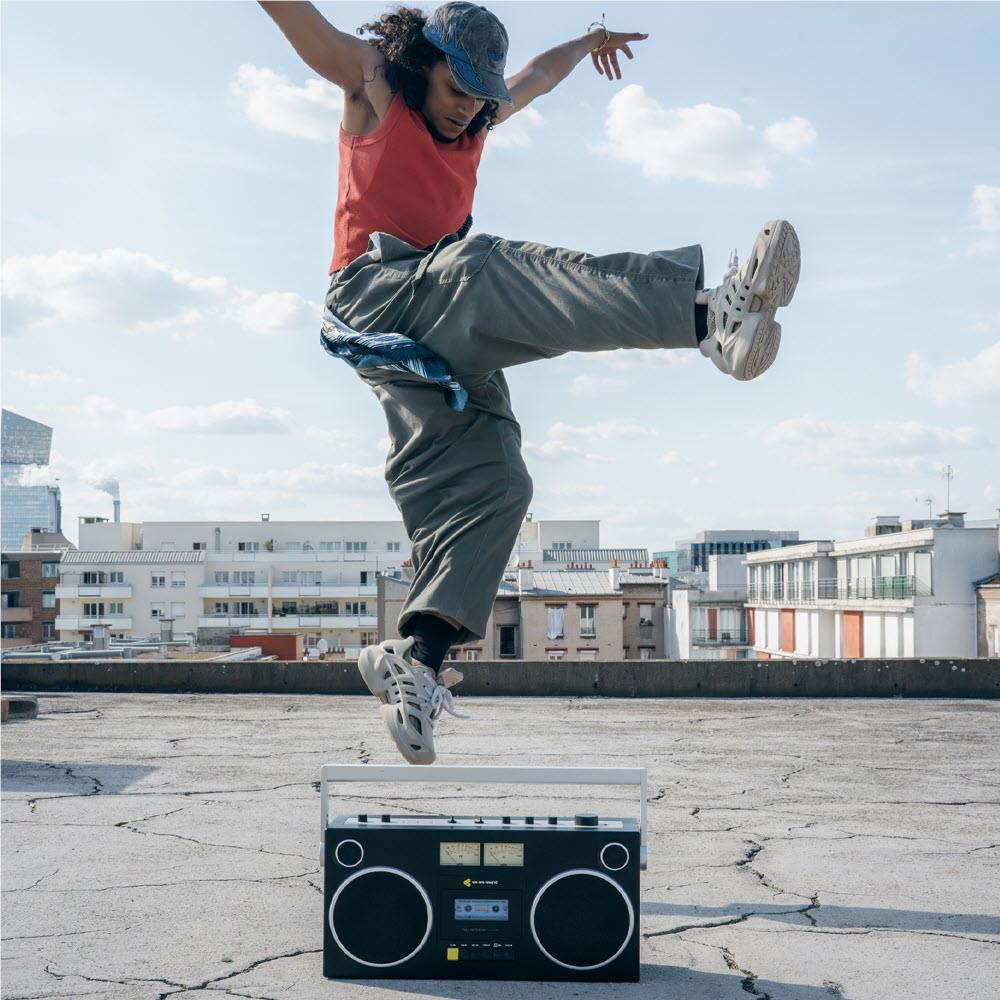 Black cassette boombox on ground with two speaker grilles and tuning dials