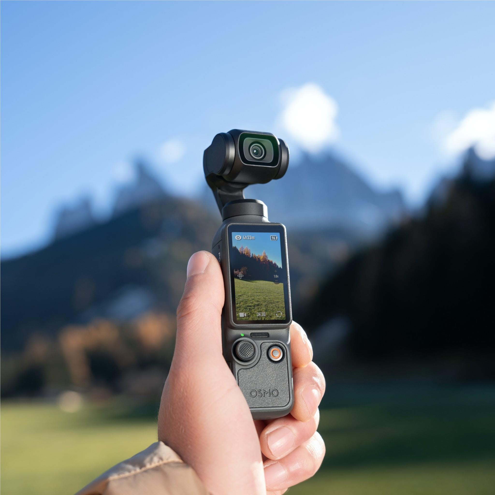 DJI gimbal camera held in one hand with active touchscreen display