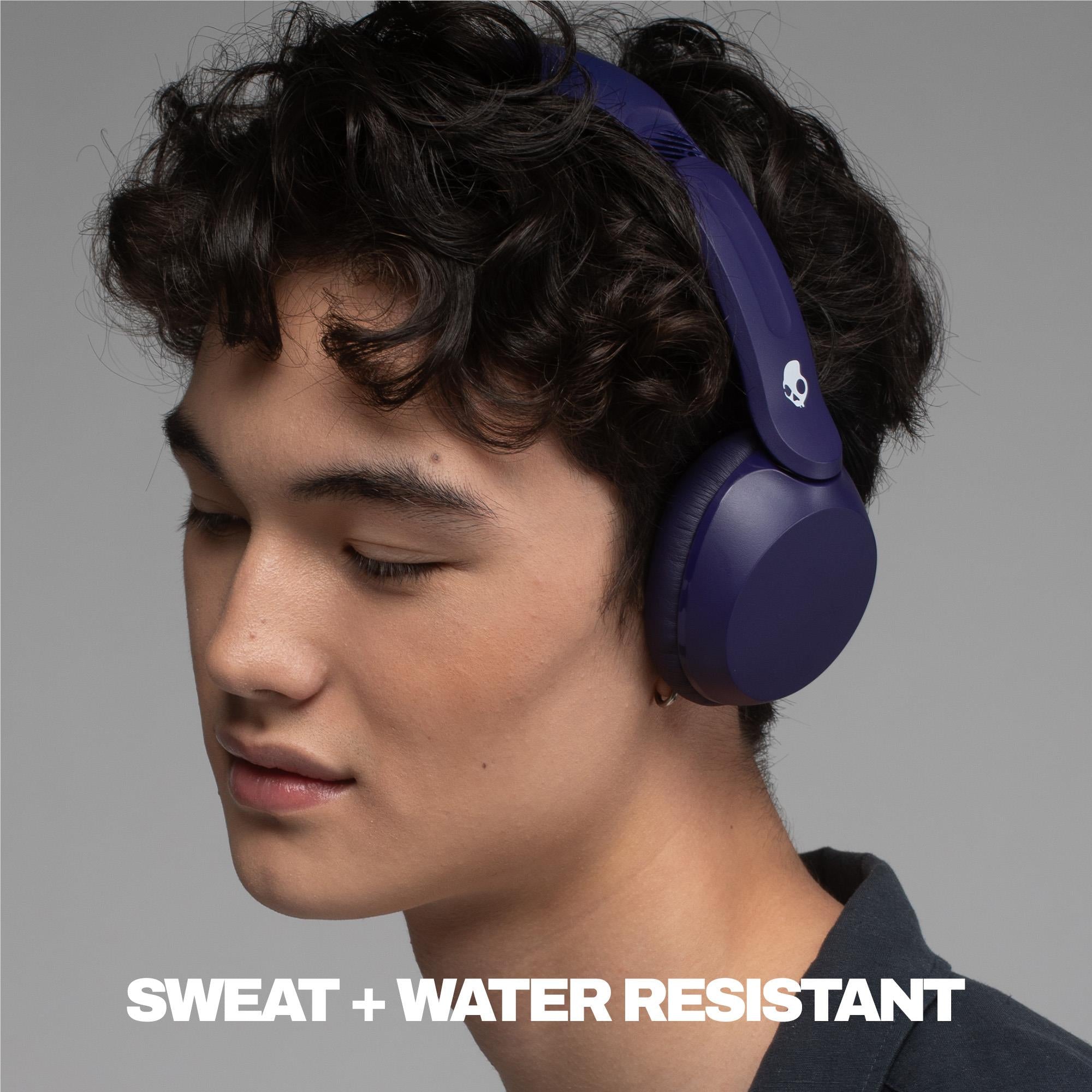 Wireless over-ear headphones worn over curly hair, dark purple ear cups and headband