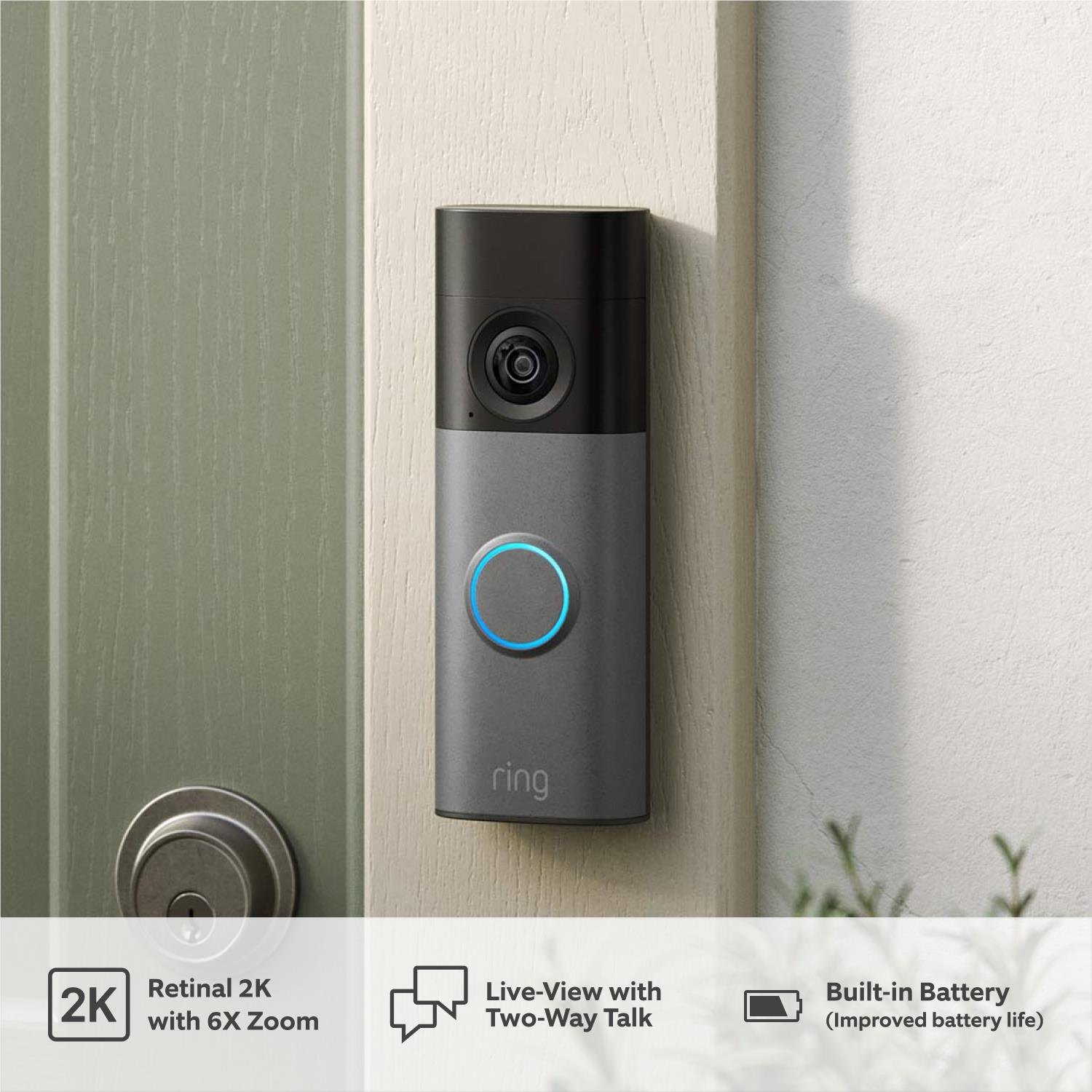 Speckle grey battery video doorbell mounted on wall with black camera lens and blue ring