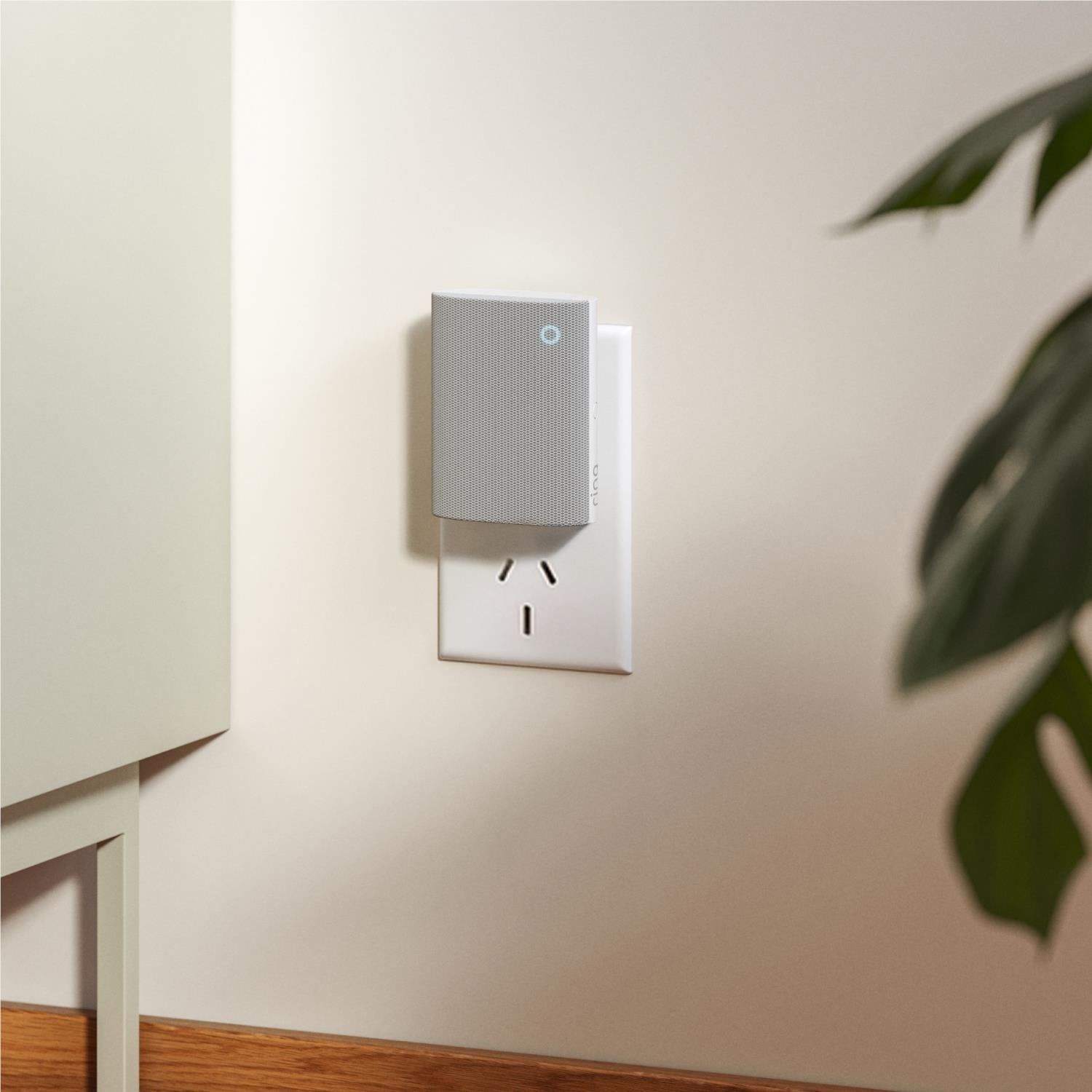 Gray plug-in doorbell chime mounted on wall outlet with blue indicator light