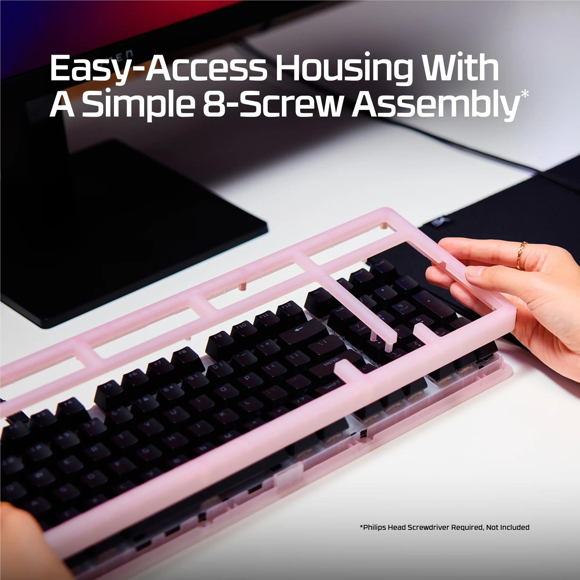 Mechanical keyboard with a pink frame, showing a hand lifting a keycap