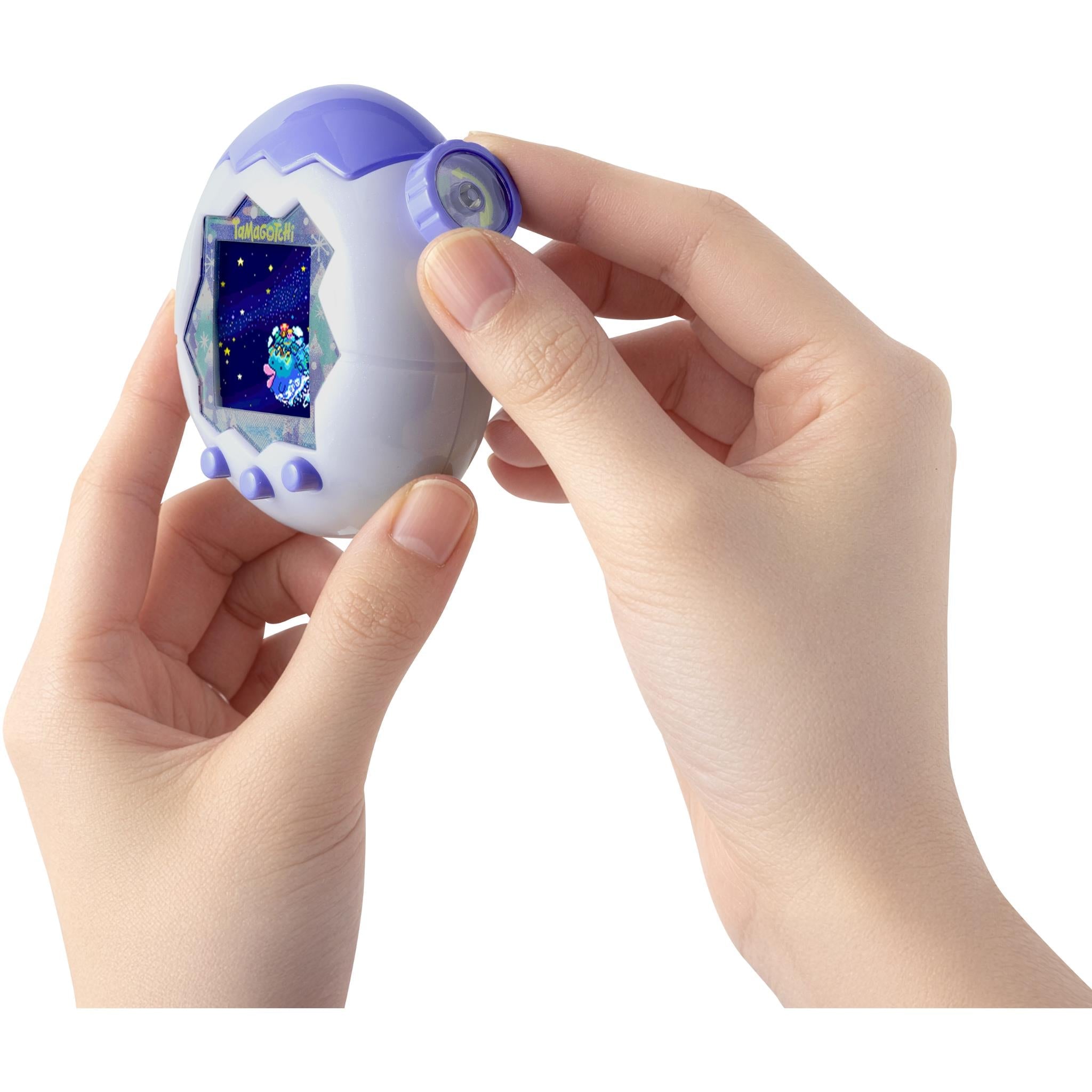 Hands holding a white and blue digital pet, top dial near the screen