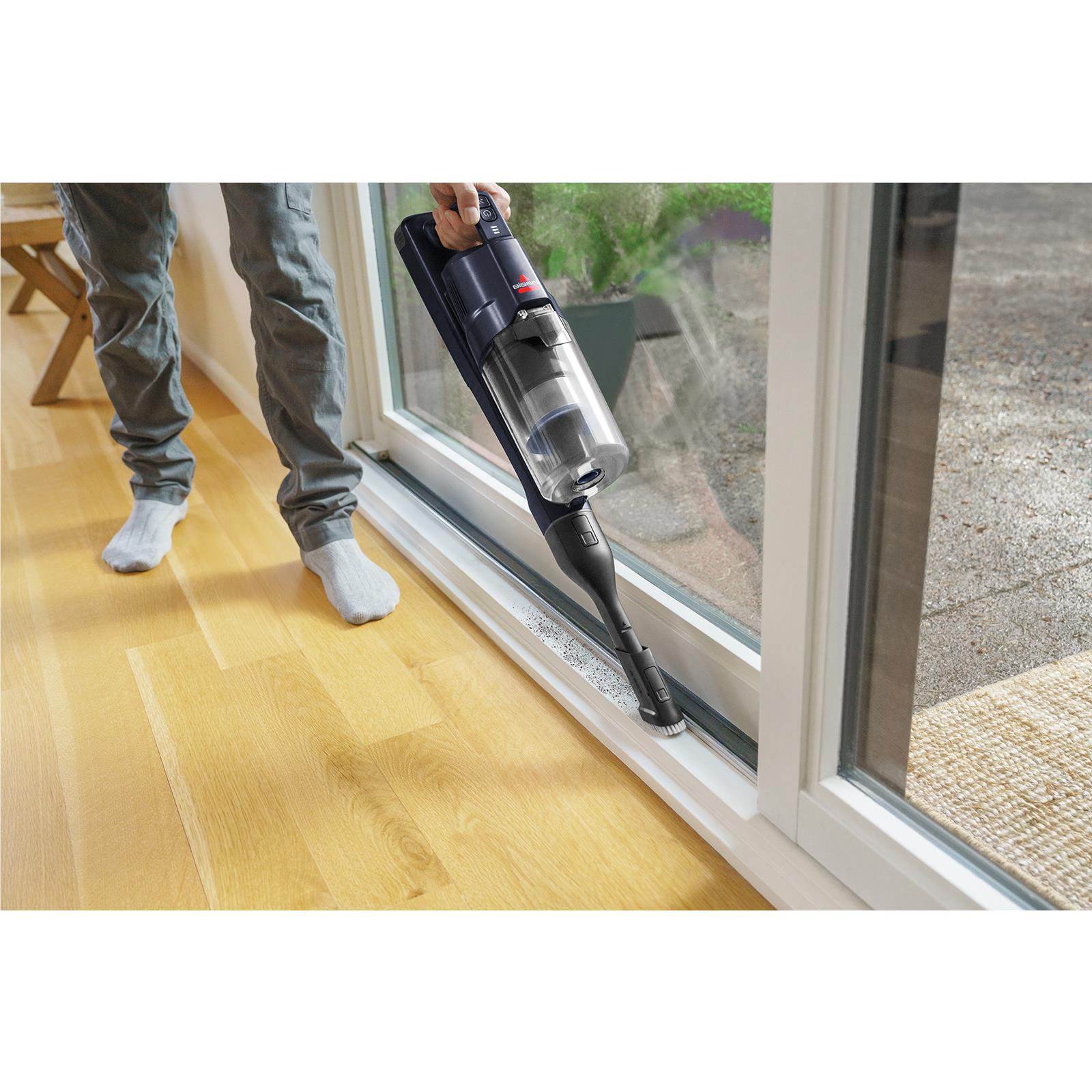 Bissell PowerClean cordless stick vacuum cleaning along window floor edge