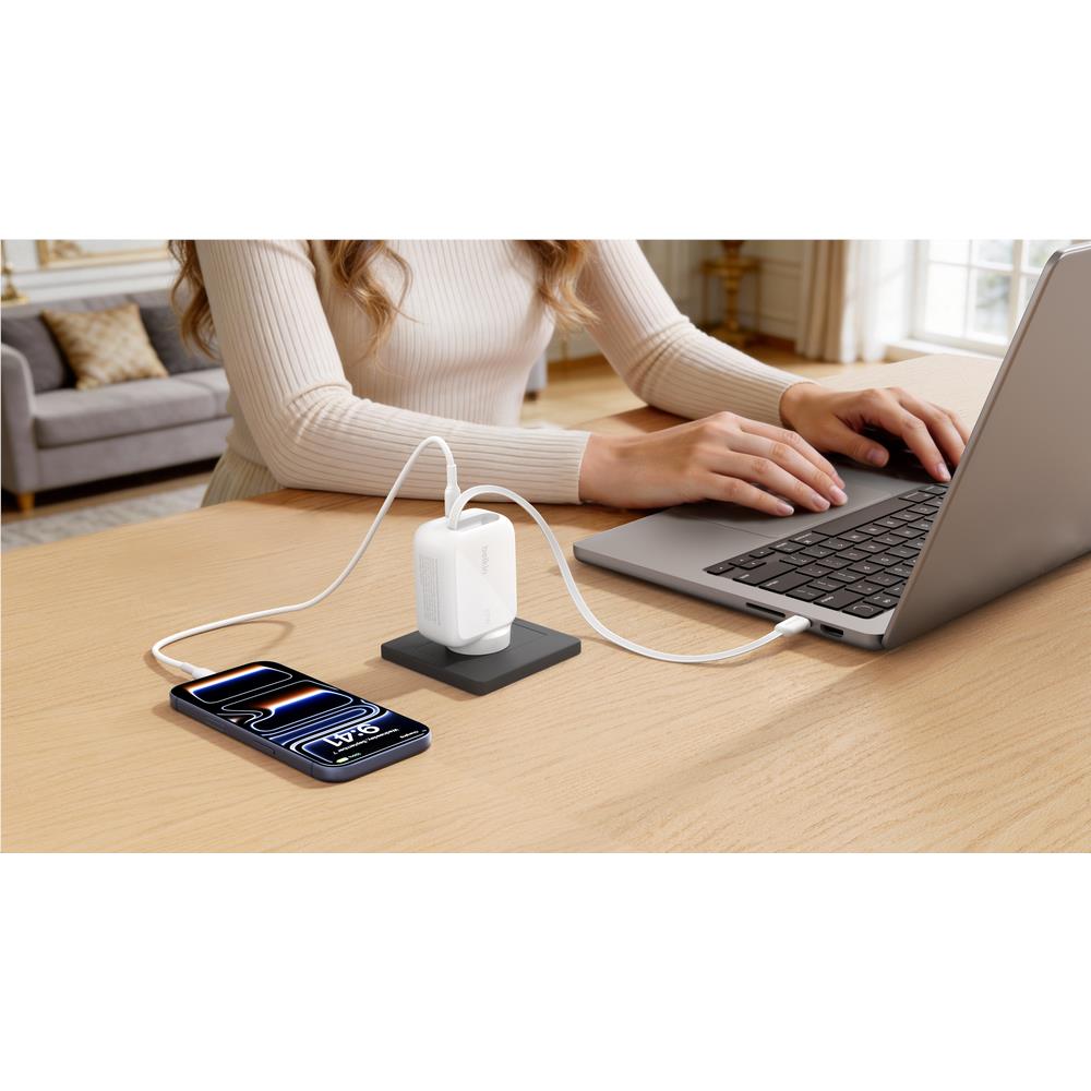 Belkin 67W USB-C charger with cable powering phone and laptop on desk