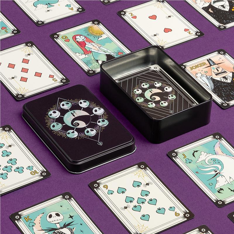 Assorted Nightmare-themed playing cards on purple background with tin in center