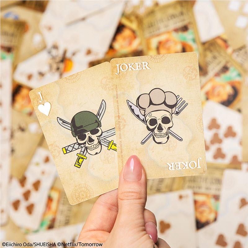 Hand holding two One Piece Joker cards with skull art and heart-suit symbols