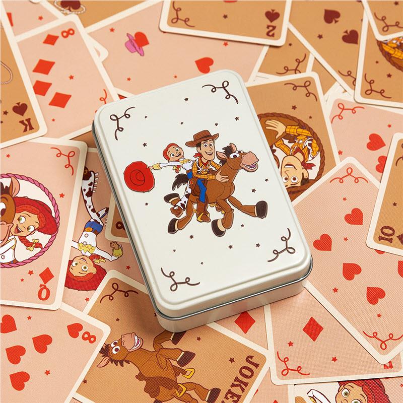 Metal playing-card tin with cowboy artwork surrounded by cards featuring hearts and spades