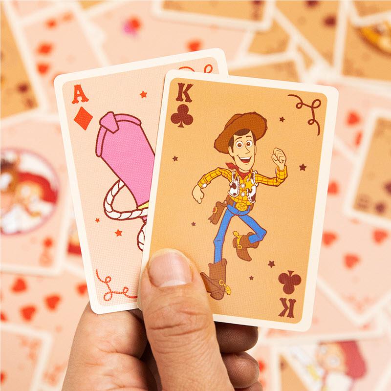 Hand holding Ace and King character playing cards with hearts and decorative suit symbols