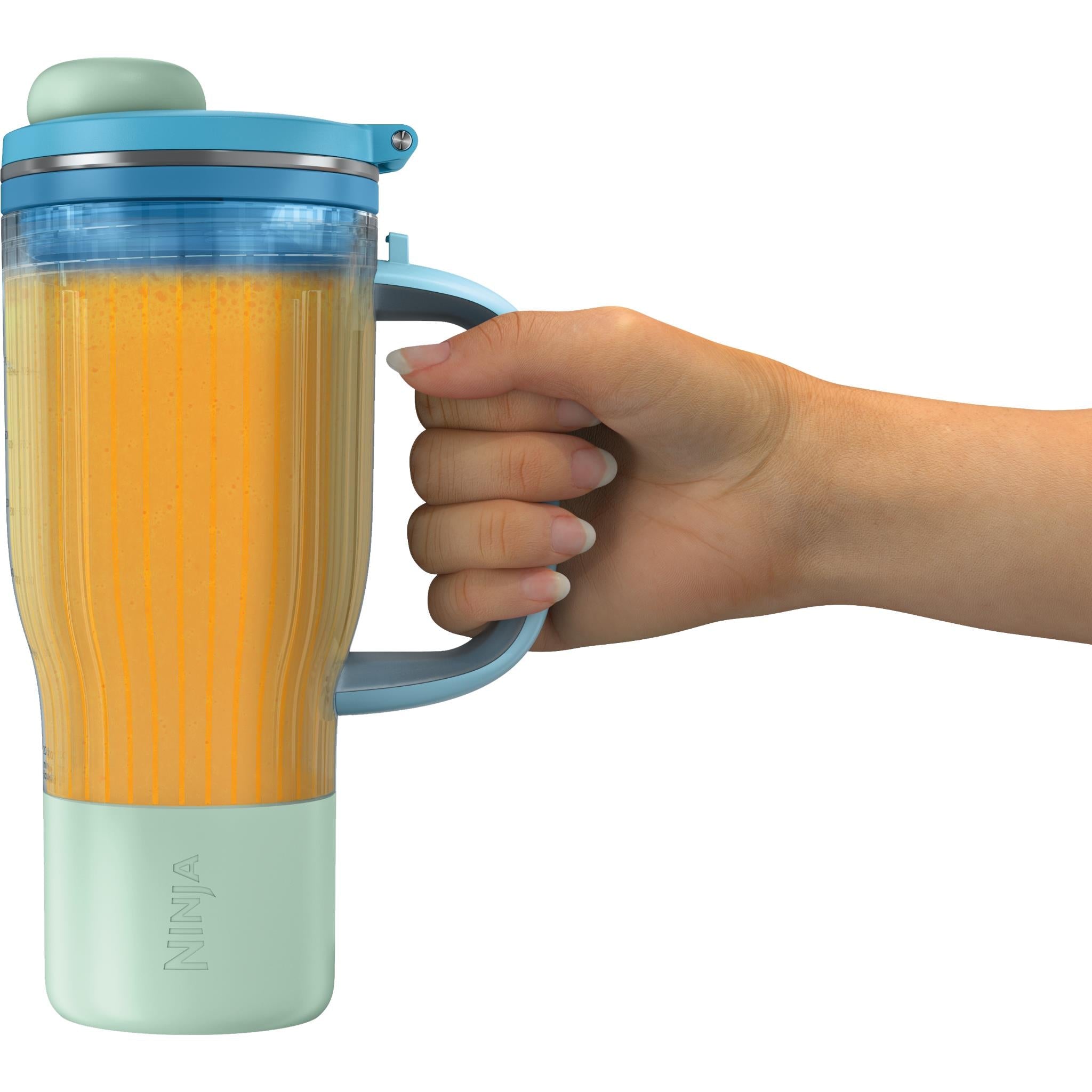 Blender and tumbler with handle, hand holding, clear cup filled with orange drink